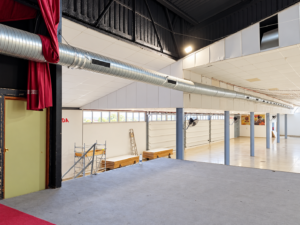 Gran salón industrial con escenario y conductos